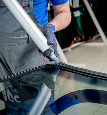 Technician running a bead of urethane along the edge of a windshield