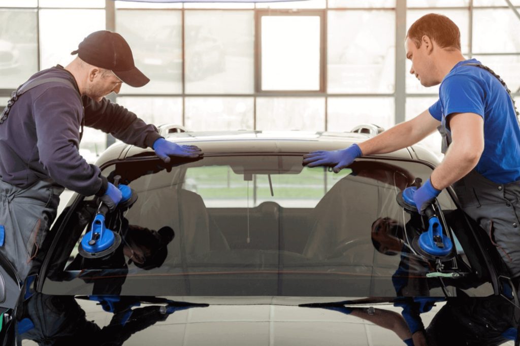 Two technicians setting a new windshield into place